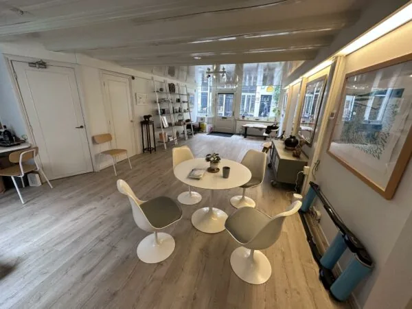Een modern ingerichte ruimte aan de Eerste Lindendwarsstraat met een ronde tafel, designstoelen en kunst aan de muur.
